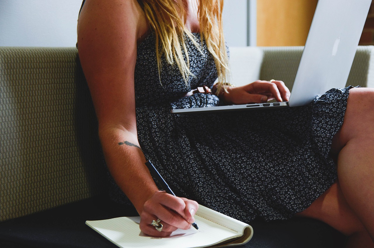 Woman carrying a laptop and writing on a notebook