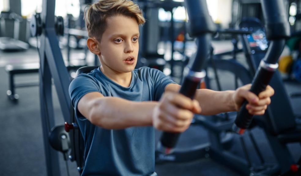 A young boy focused on his form while using a chest press machine at a fitness gym