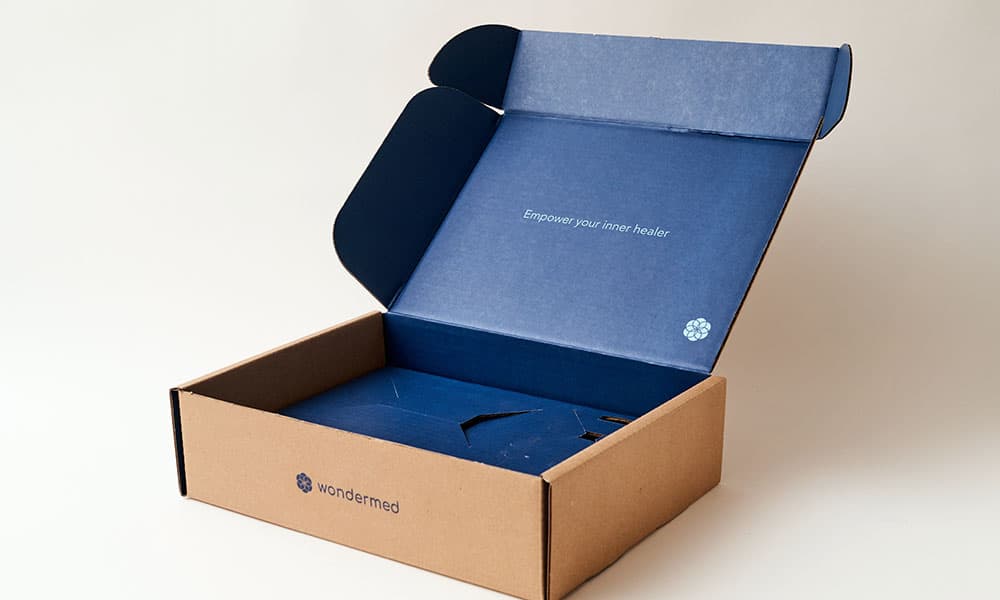 An open cardboard shipping box with blue interior text that reads "Empower your inner healer"