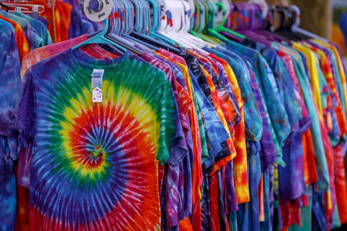 Racks of various colorful tie-dye t-shirts hanging for sale, displaying vibrant patterns and designs